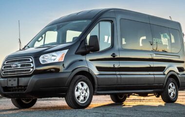 Black Ford 15 passenger midroof rental van with Greenvans logo on side