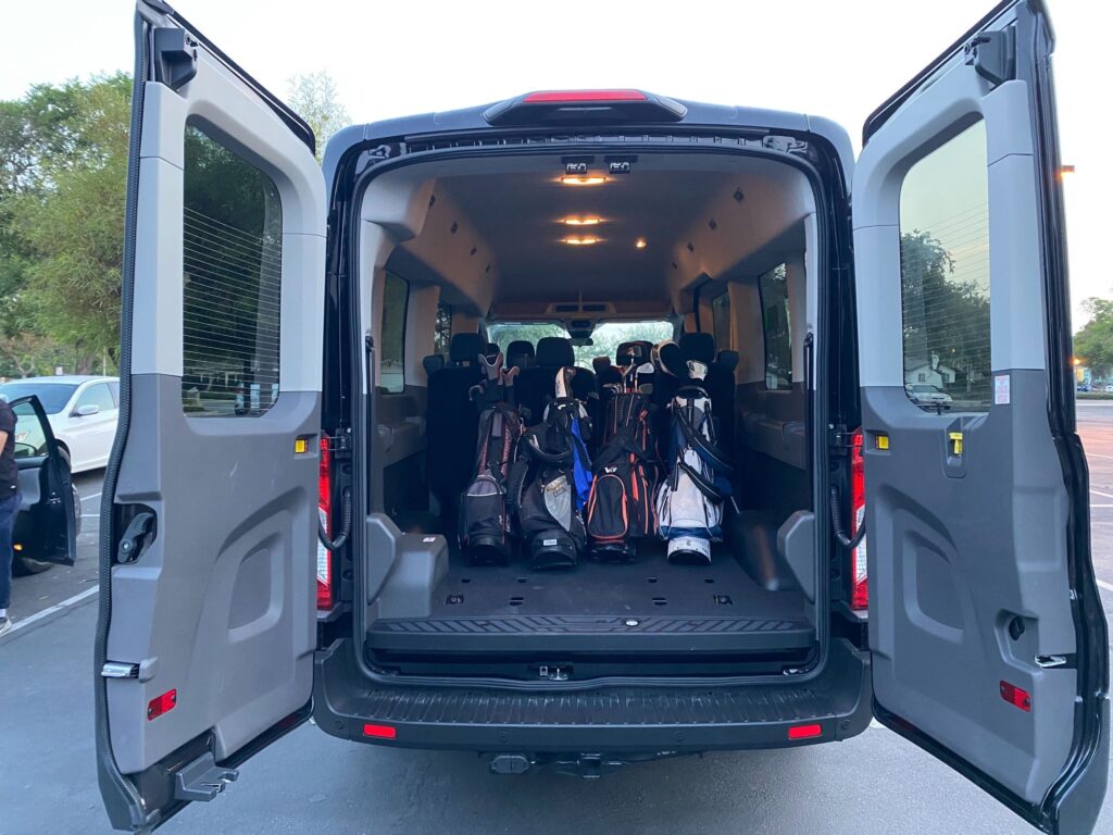Interior of Ford 15 passenger van with four bags of golf clubs inside