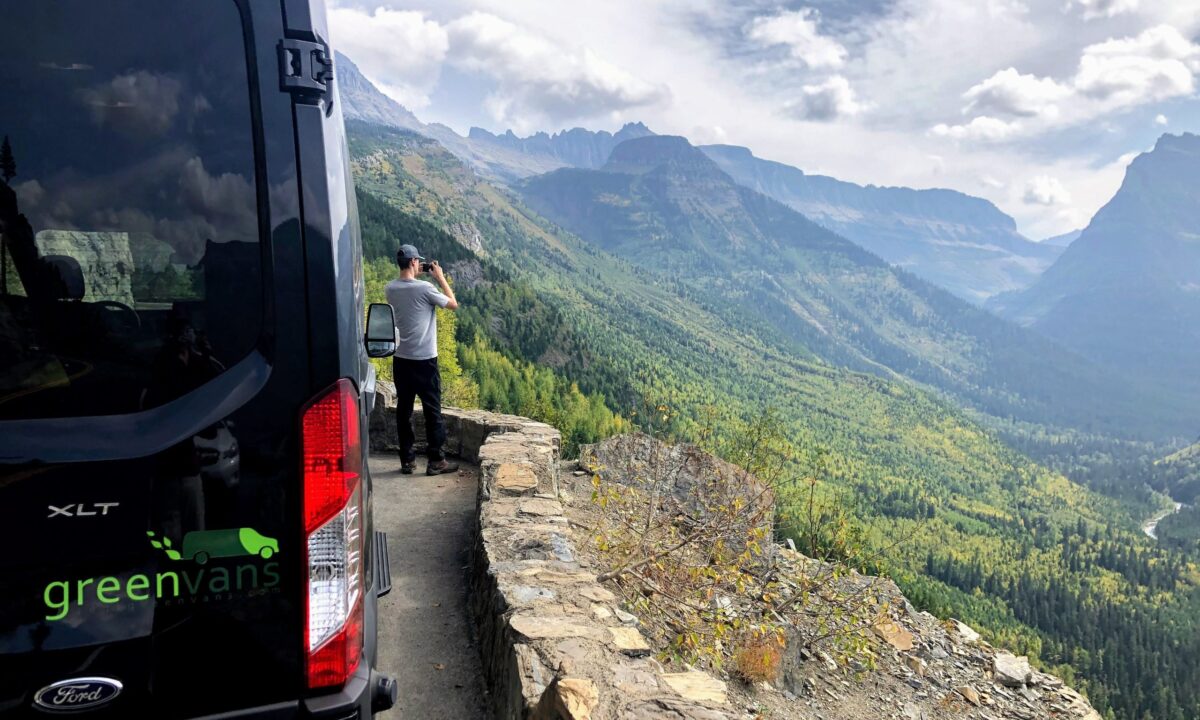 Male tourist overlooking Mammoth Mountain outside of is Ford 15 passenger van rental from Greenvans