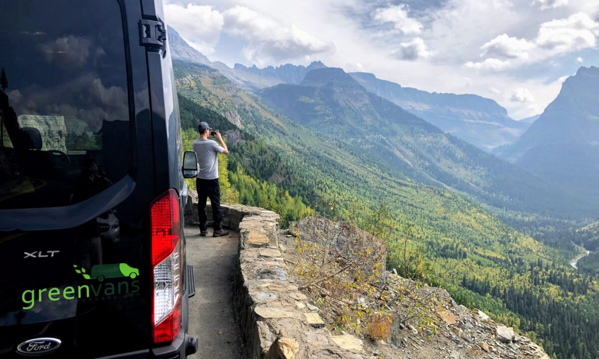 A male tourist overlooking Mammoth Mountain outside of his Ford 15 passenger van rental from Greenvans