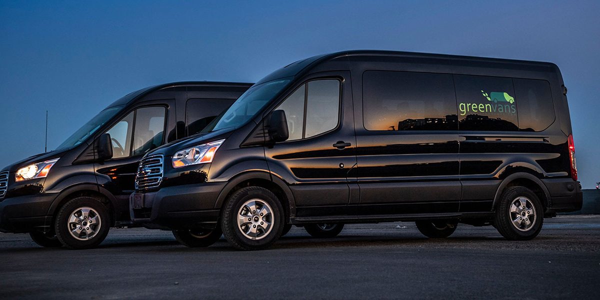 Side view of two Ford Transit 15-passenger rental vans with the Greenvans logo