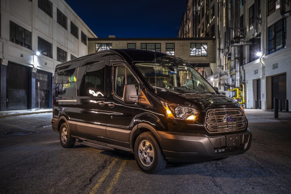 Exterior of a Greenvans transit 15 passenger rental van parked in the city at night