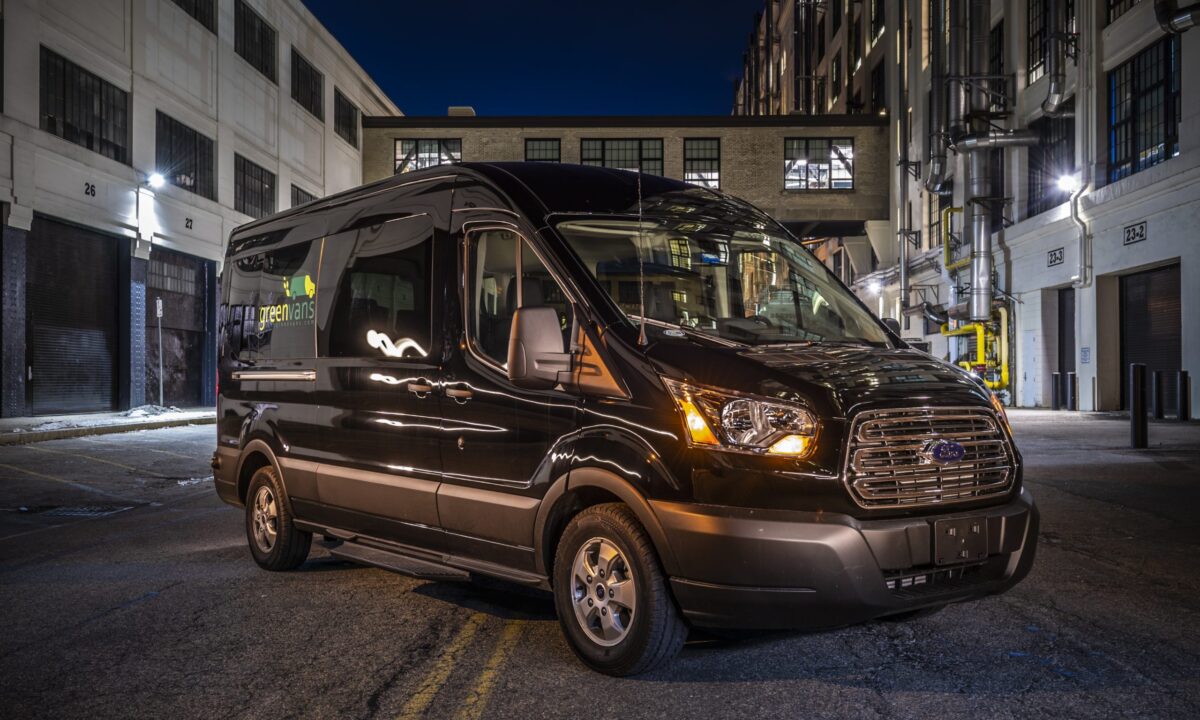 Exterior of a Greenvans transit 15 passenger rental van parked in the city at night