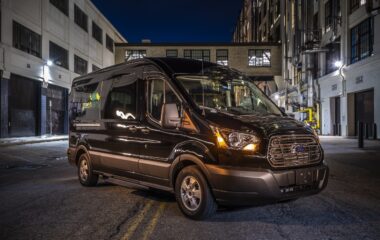 Exterior of a Greenvans transit 15 passenger rental van parked in the city at night