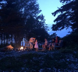 Family of six sitting by campfire on the coast of Maine