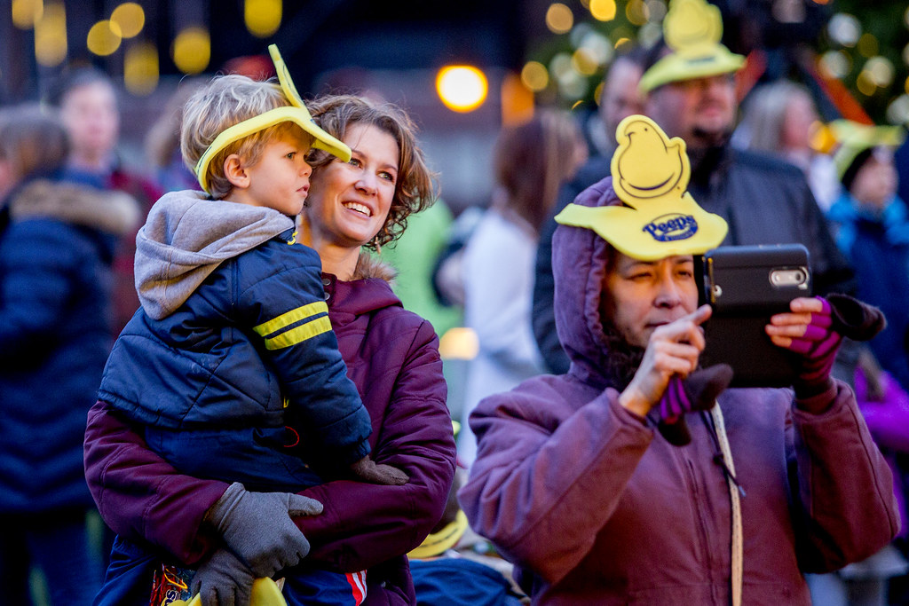 A young family of three at a New Year's celebration wearing Peep's visors and taking videos