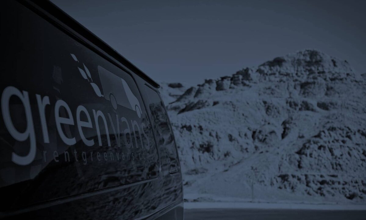 Side image of a Greenvans 15-passenger van rental Ford Transit 350 XLT with snowy mountains in background