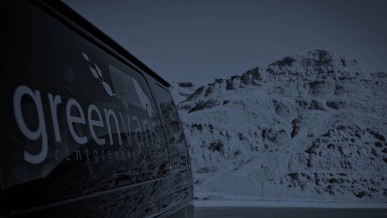 Side image of a Greenvans 15-passenger van rental Ford Transit 350 XLT with snowy mountains in background