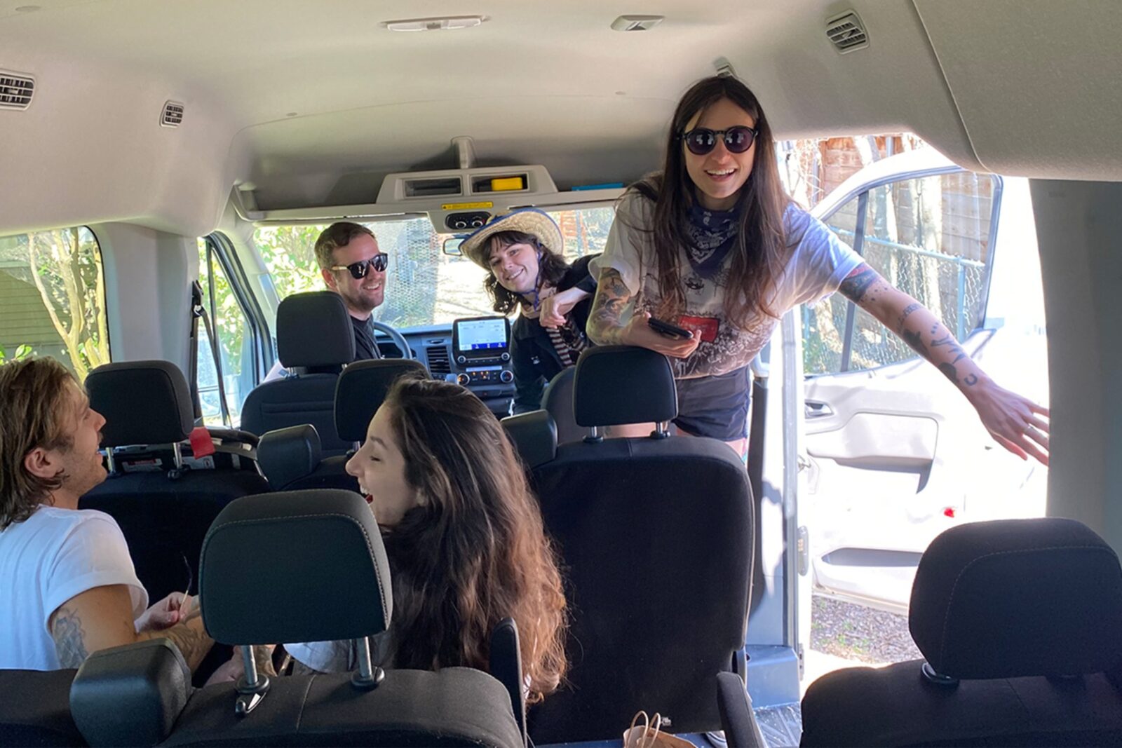 Five people getting settled into a Greenvans 15-passenger van