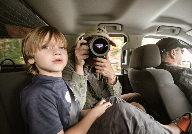 A family of three inside a Greenvans rental with passengers looking out the window and taking pictures