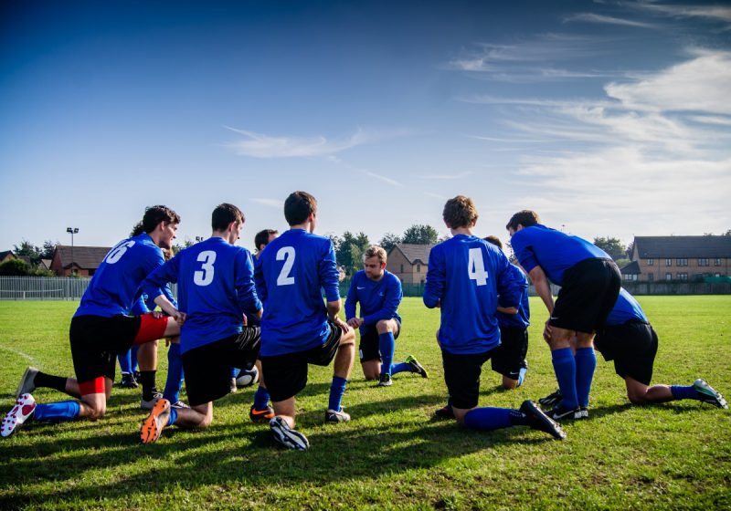 A sports team on the field wearing blue jerseys with white numbers