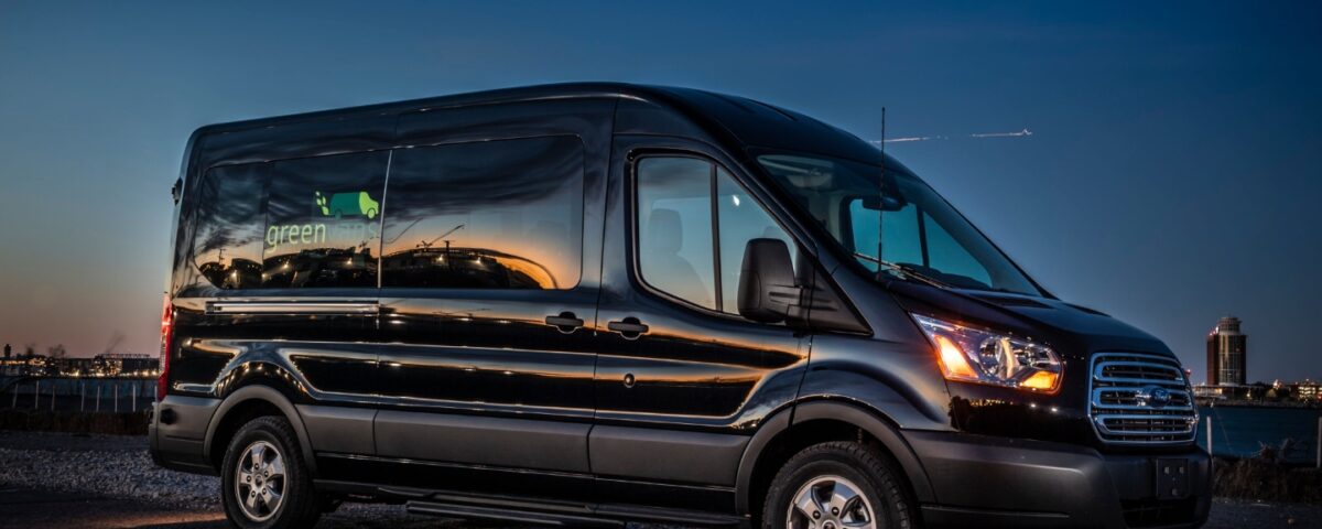 Side view of Ford 15 Passenger Medium Roof Transit Rental Van with Greenvans logo