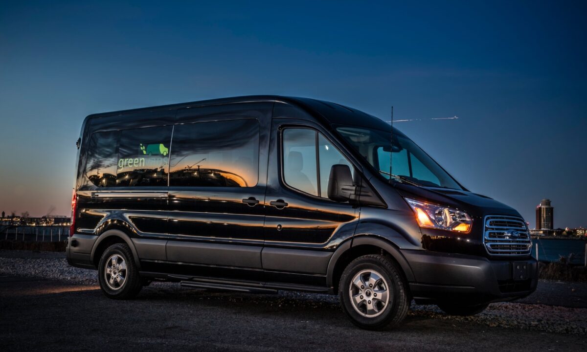 Side view of Ford 15 Passenger Medium Roof Transit Rental Van with Greenvans logo