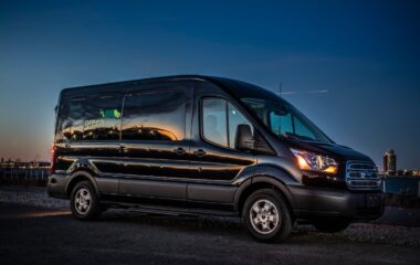 Side view of Ford 15 Passenger Medium Roof Transit Rental Van with Greenvans logo
