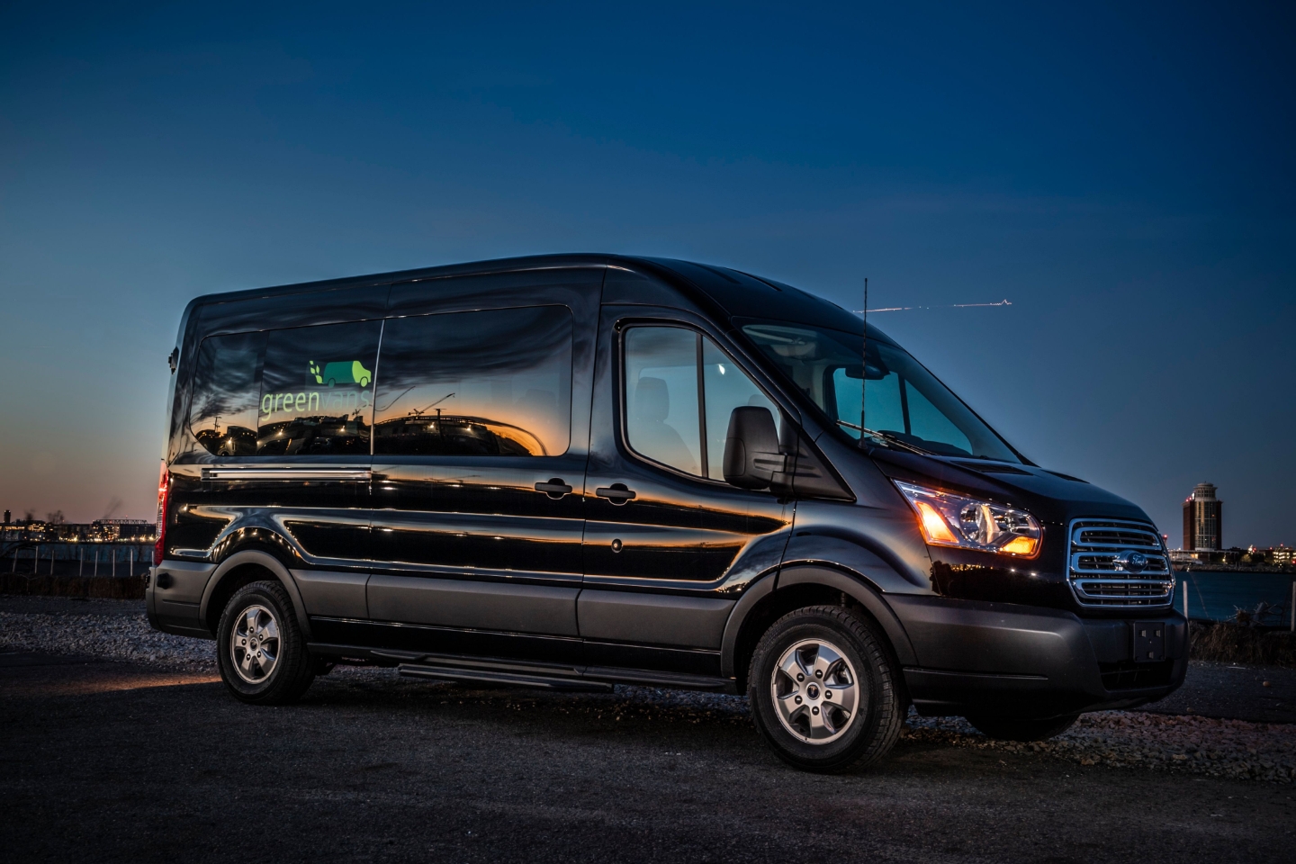 Side view of Ford 15 Passenger Medium Roof Transit Rental Van with Greenvans logo