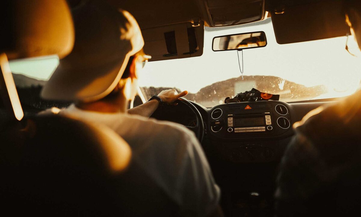 Man wearing baseball cap backwards driving a Greenvans 15 passenger rental van