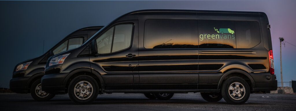 Side view of two Ford Medium Roof Transit 15 passenger rental vans at night.