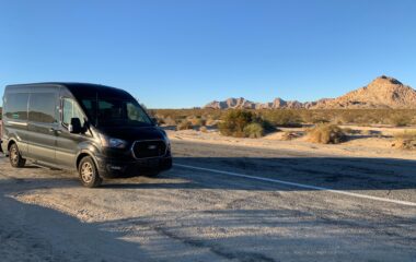 Side view of two Ford Medium Roof Transit 15 passenger rental vans at night.