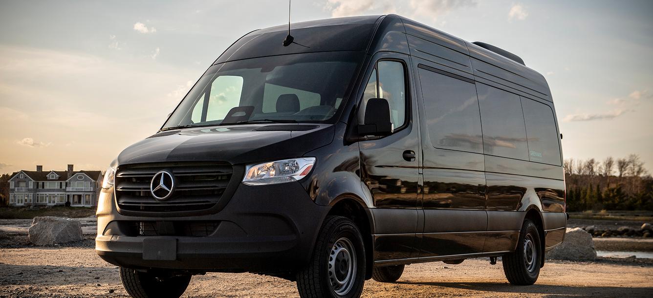 15-passenger Mercedes-Benz Sprinter 2500 high-roof van parked on a gravel road near a coastal home
